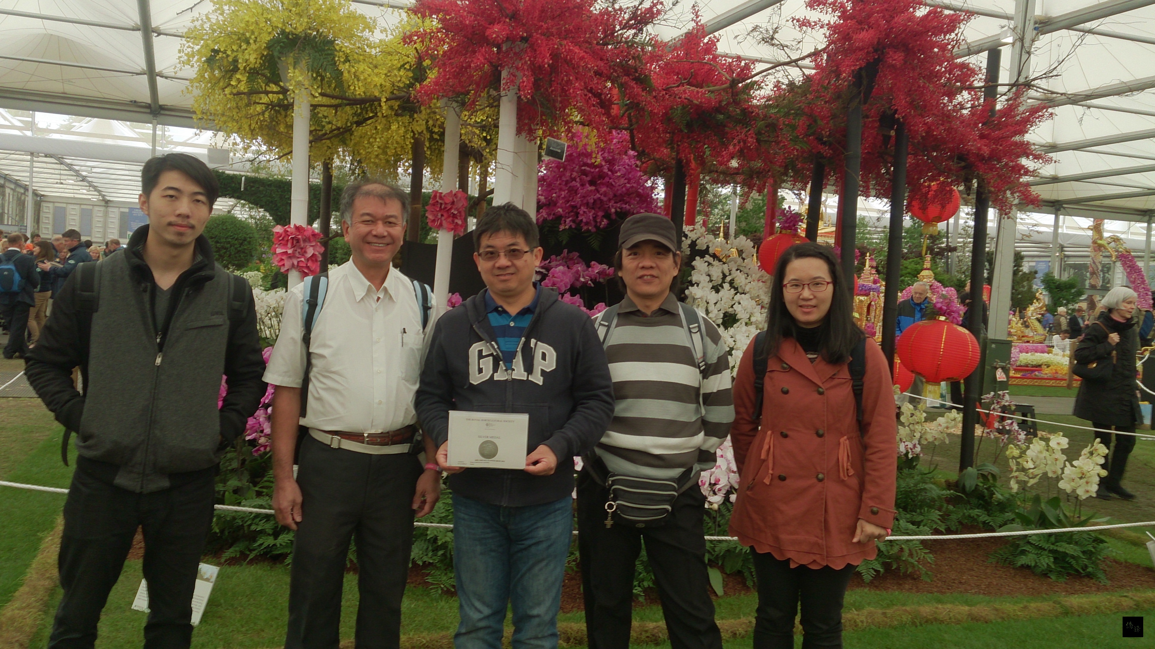 英國切爾西花展19日登場，主辦單位皇家園藝協會公布評審結果，台灣展攤獲銀牌獎。台灣蘭花產銷發展協會秘書長曾俊弼（中）與設計總監林賢（左二）等人合影。（中央社提供）