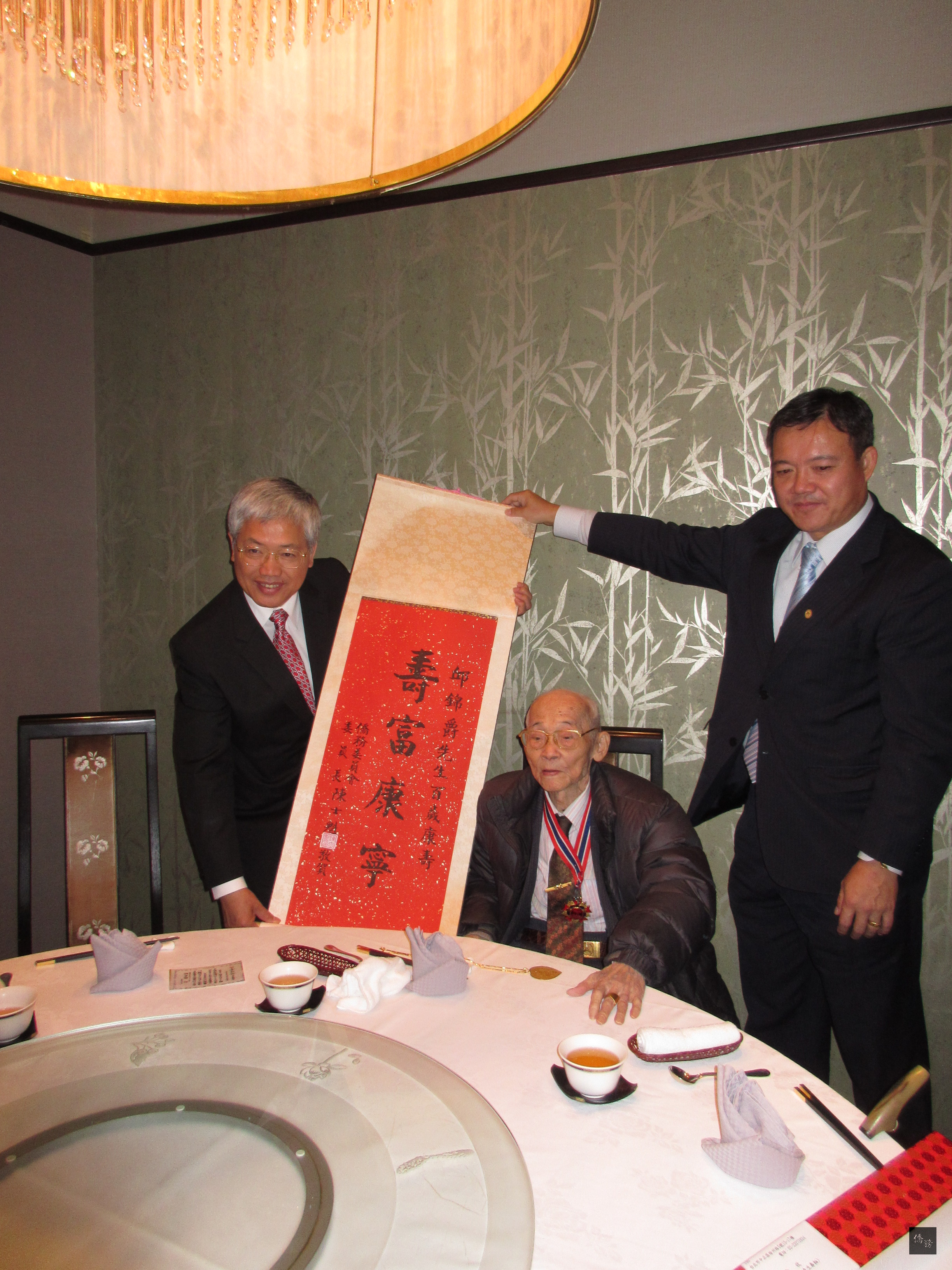 陳委員長（左）頒贈百歲掛軸給名古屋華僑總會名譽會長邱錦爵（中）。（駐日本代表處提供）