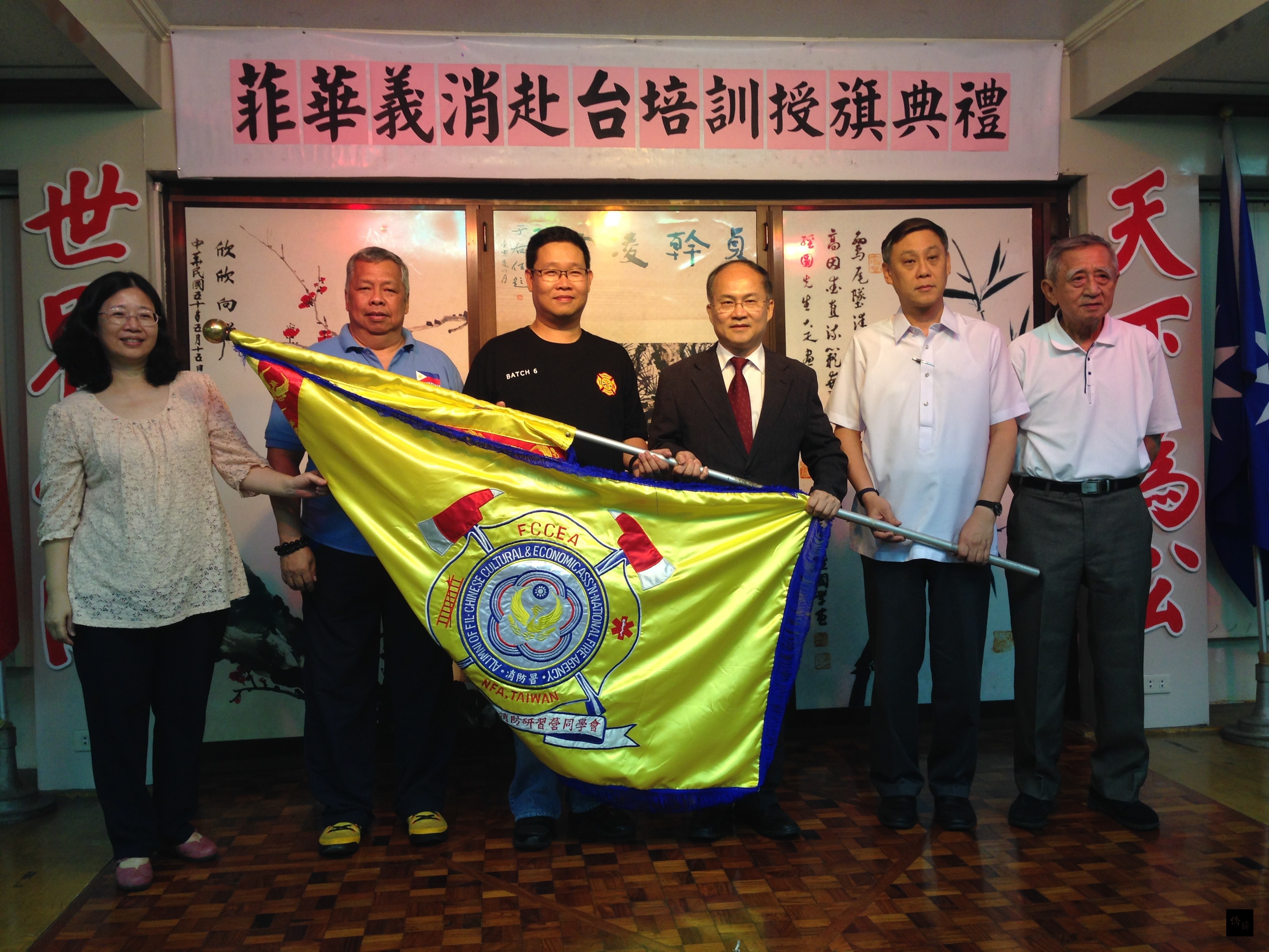 菲華文教中心主任吳學誠、菲華文經總會常務委員王家鵬為2015年菲華僑商青年消防研習營授旗。（菲華文教中心提供）