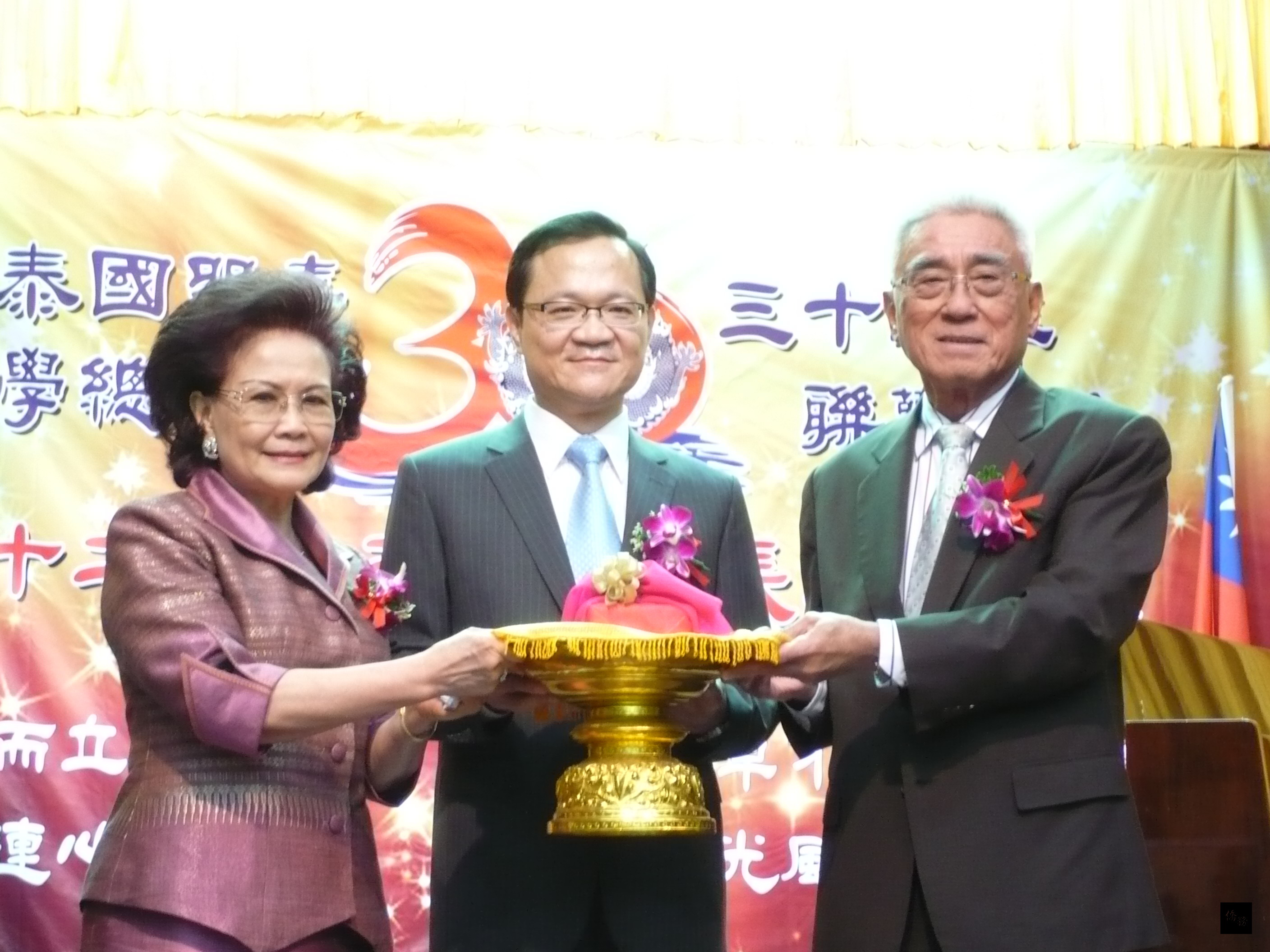 在駐泰國副代表丁樂群(中)監交下,泰國留臺同學總會卸任理事長洪鈞濤(右)交接給新任理事長丘菁瑛(左)。(泰華文教中心提供)