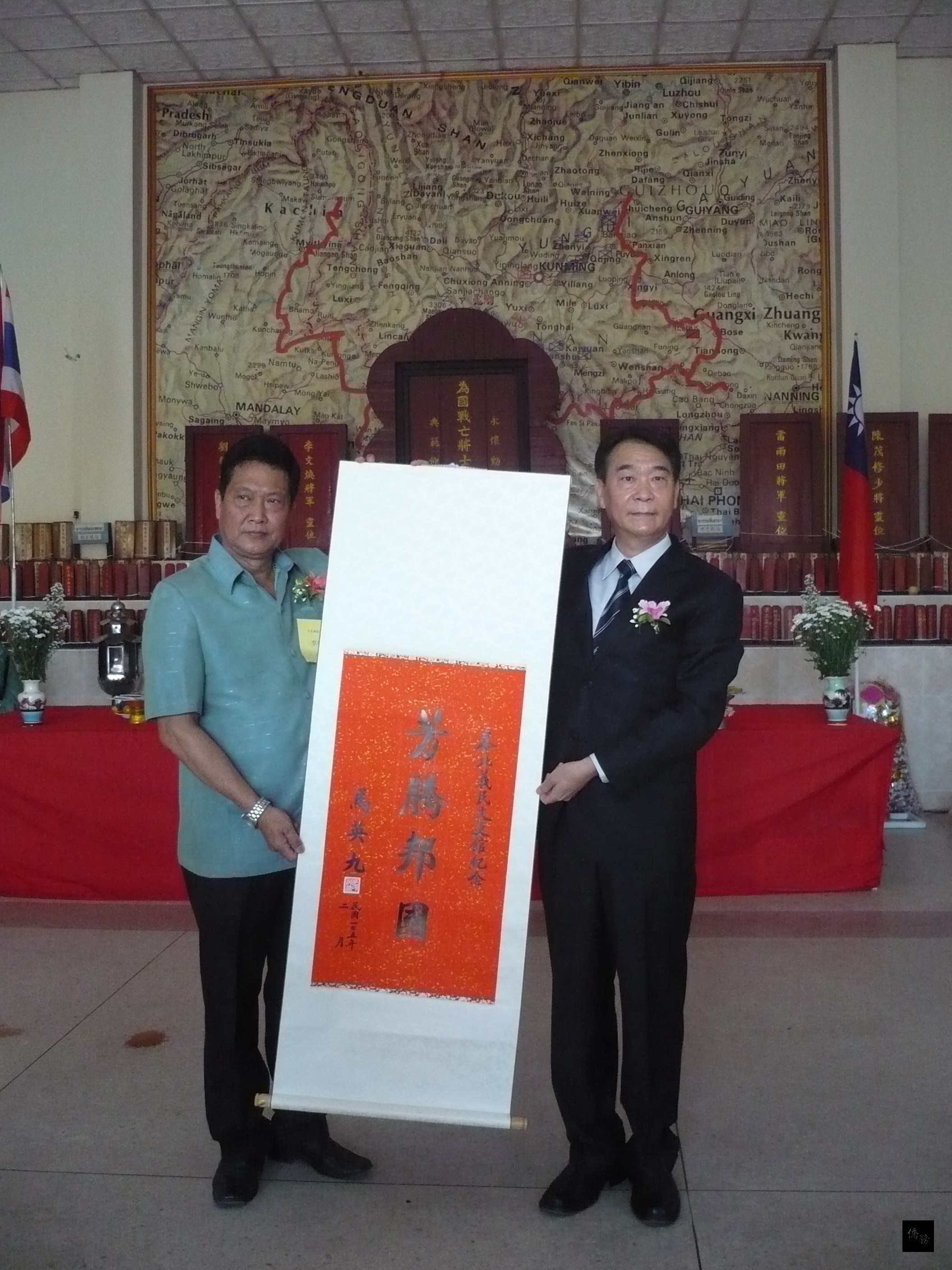 泰華文教中心副主任蔣翼鵬(右)代表將總統馬英九題贈的中堂致贈給義民文史館主任委員李泰增(左)。(泰華文教中心提供)