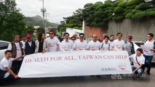 唐殿文（前右4）、趙慶泰（前右5）、李寶禮（前右3）18日在首爾北漢山公園前手持印有「Health for all, Taiwan can help」布條，在國旗前為支持臺灣參與世界衛生大會展開健走。（中央社提供）