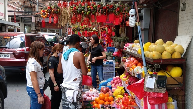 水果攤販擺滿各式各樣綁有紅色彩帶的水果。