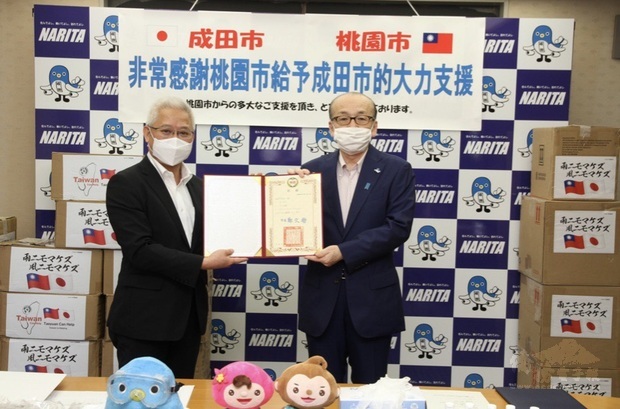 鍾幸昌(左)代表捐贈物資予成田市,由小泉一成(右)接受。