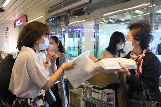 何素珍一一分送防護衣給搭乘專機的臺灣鄉親。