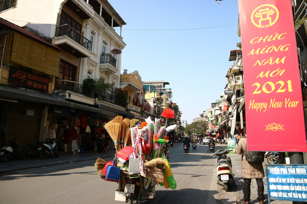 多數越南民眾的新年願望就是能早日揮別2019冠狀病毒疾病(COVID-19,武漢肺炎)疫情,讓生活重回正軌。圖為賣掃帚與家用五金的機車小販於109年12月31日疾駛而過河內街頭迎接2021年的看板。