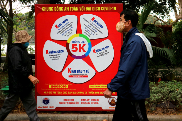 越南2020年成功防疫打響國際名聲,在政府大力宣導下,民眾防疫意識提升,出入公共場所都會戴上口罩。圖為109年12月31日在還劍湖散步的民眾經過寫有「5K」防疫標語的招牌。