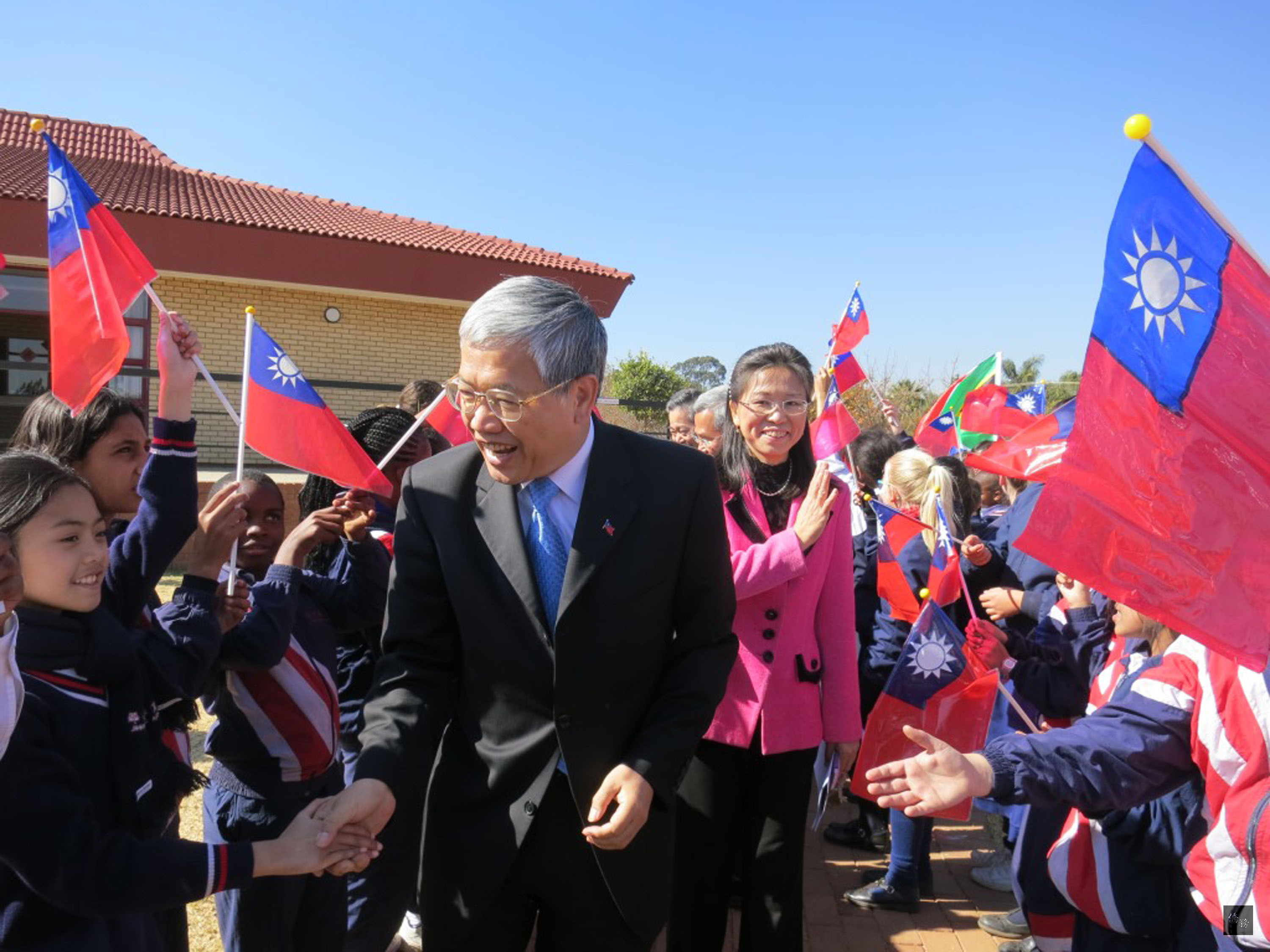 僑委會委員長陳士魁(前中)拜訪南非斐京華僑公學,學生手中揮舞著中華民國國旗,夾道熱烈歡迎。(中央社提供)