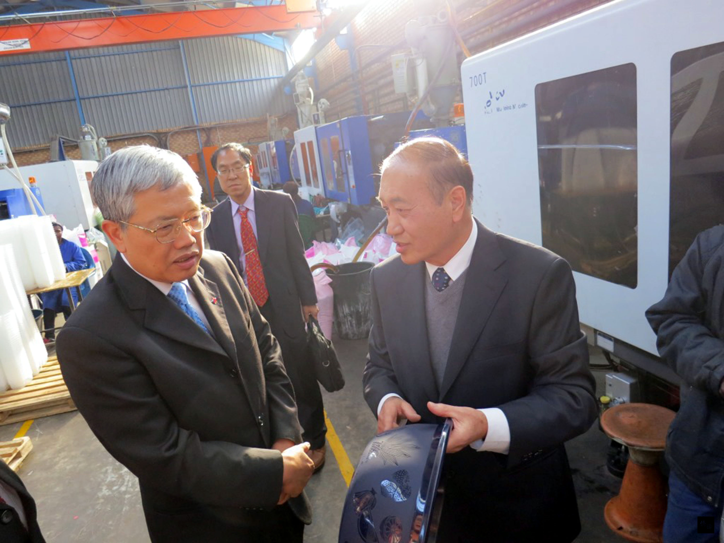 陳委員長(左)拜訪南非台商楊純明的塑膠工廠,並仔細聆聽解說。(中央社提供)