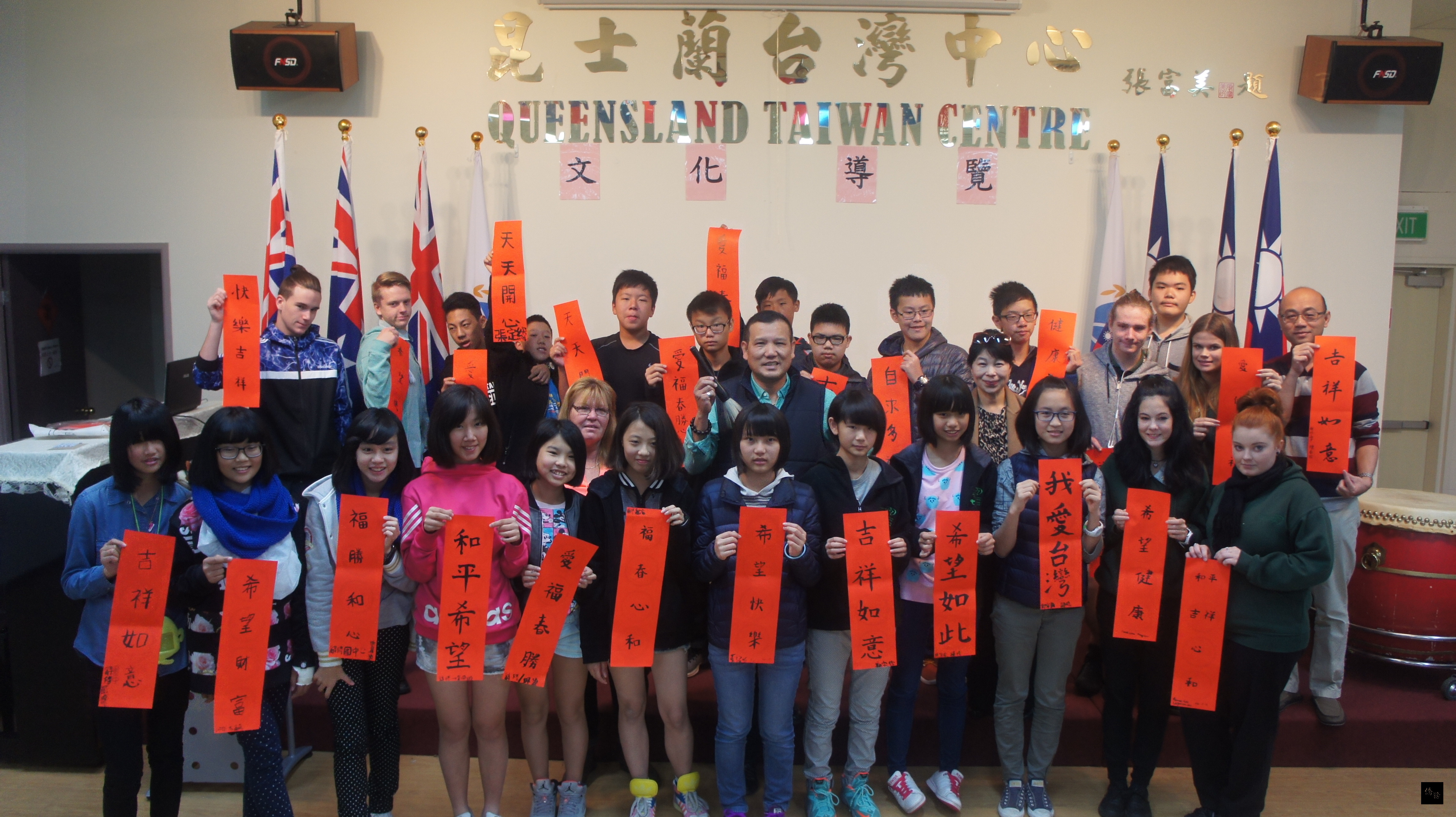 昆州Loganlea State High School與姐妹校新北市辭修高中參觀布里斯本僑教中心,在謙光書道會林俊傑老師(持毛筆者)教授下,親筆書寫吉祥話。(布里斯本僑教中心提供)