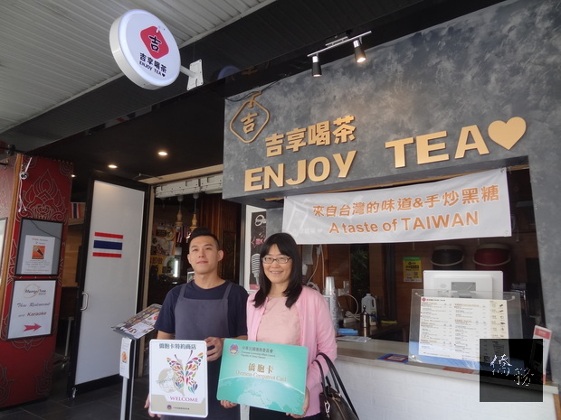 吳春芳(右) 頒贈僑胞卡特約商店識別貼紙及僑胞卡樣張予業者盧先生(左)。