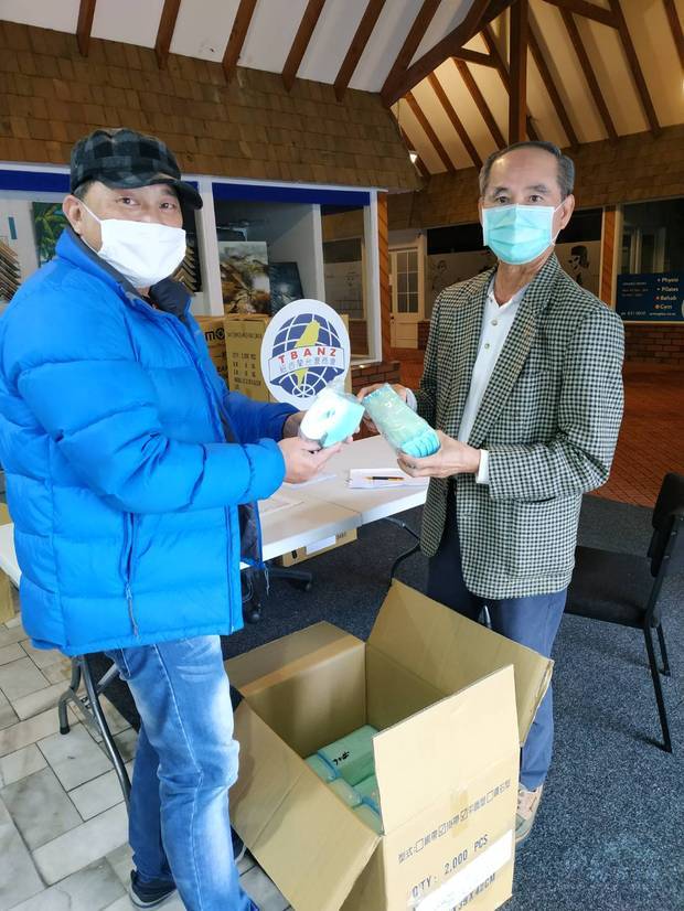 僑胞領口罩，左為會長黃柏誠，右為僑務委員楊貴森。