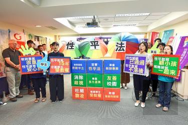 People hold signs at a news conference in Taipei yesterday calling on the government to work harder to achieve gender equality in schools./Photo courtesy of Taipei Times
