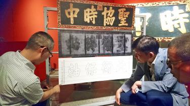 I-Kuan Tao College professor of conservation science Lin Ren-chen inspects a Qing Dynasty imperial inscription and an X-ray of characters hidden beneath its surface in Tainan yesterday./Photo courtesy of Taipei Times