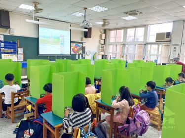 Pupils at the Chienkung Elementary School in Hsinchu yesterday eat lunch separated by isolation panels fashioned by their teacher as part of disease-prevention measures./Photo courtesy of Taipei Times