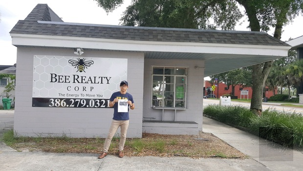 2019年 6 月25日,大兒子啟瑋拿著昔日壁畫的相片在換成房地產經紀商廣告旁留影。