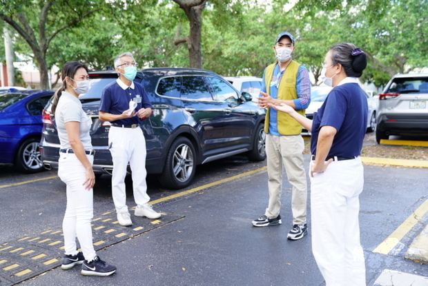 剛完成捐贈的慈濟邁阿密聯絡處志工在停車場上開始商討下一次的口罩捐贈事宜。（世界日報提供）