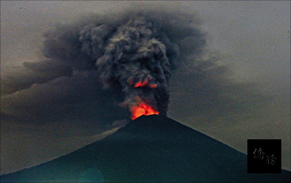 印尼當局已將峇里島阿貢火山的警戒程度調升至四級，並嚴防災情進一步擴大，持續兩個月的火山危機已重創峇里島觀光業，據報導，經濟損失約一．五億美元（約四十五．三億台幣）。圖為該火山廿七日的一景，冒出的煙霧、火焰籠罩在火山口上空。（美聯社提供）
