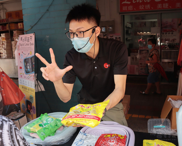 新加坡西海岸傳統市場裡傳來熟悉的台灣夜市叫賣聲，今年24歲的台灣囝仔黃柏勳（圖）賣力地推銷足浴中藥材，他的銷售風格充滿濃濃台灣味，吸引市場眾多目光。（中央社提供）